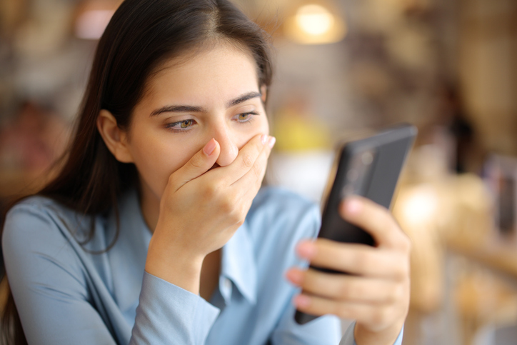 Shocked woman watching harassing text messages 