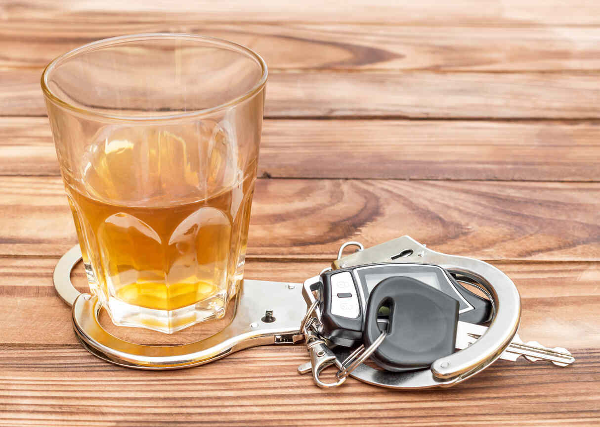 Alcohol, handcuffs, and car keys, illustrating the serious nature of a DWI arrest in Texas.