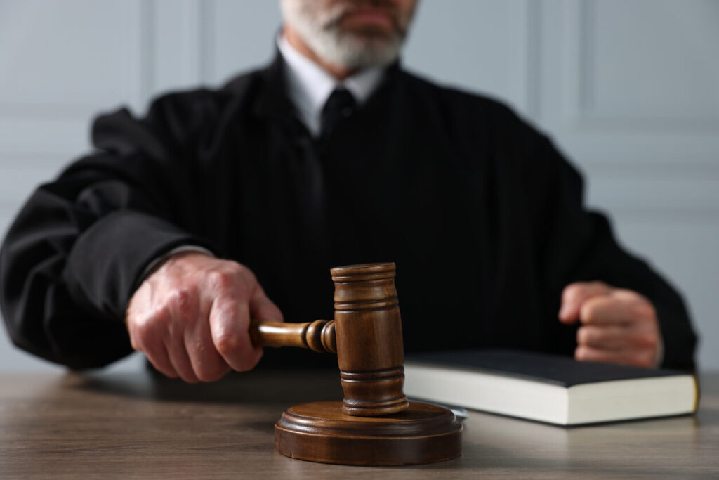 Close-up of a judge's hands on a gavel and law book, representing the authority and procedures of the immigration court system in Texas.