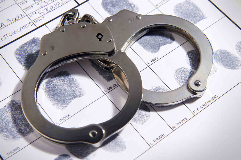 Handcuffs lying on top of a fingerprint form, symbolizing arrest and the legal system in Texas, relevant to misdemeanor and felony crimes.