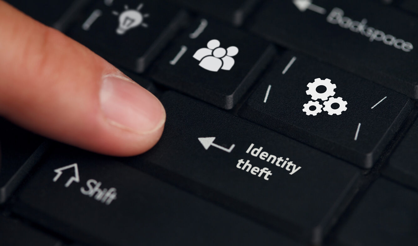 A finger poised over a keyboard key labeled 'Identity theft' with a gears icon, symbolizing the digital nature of identity theft and the legal implications under Texas law.