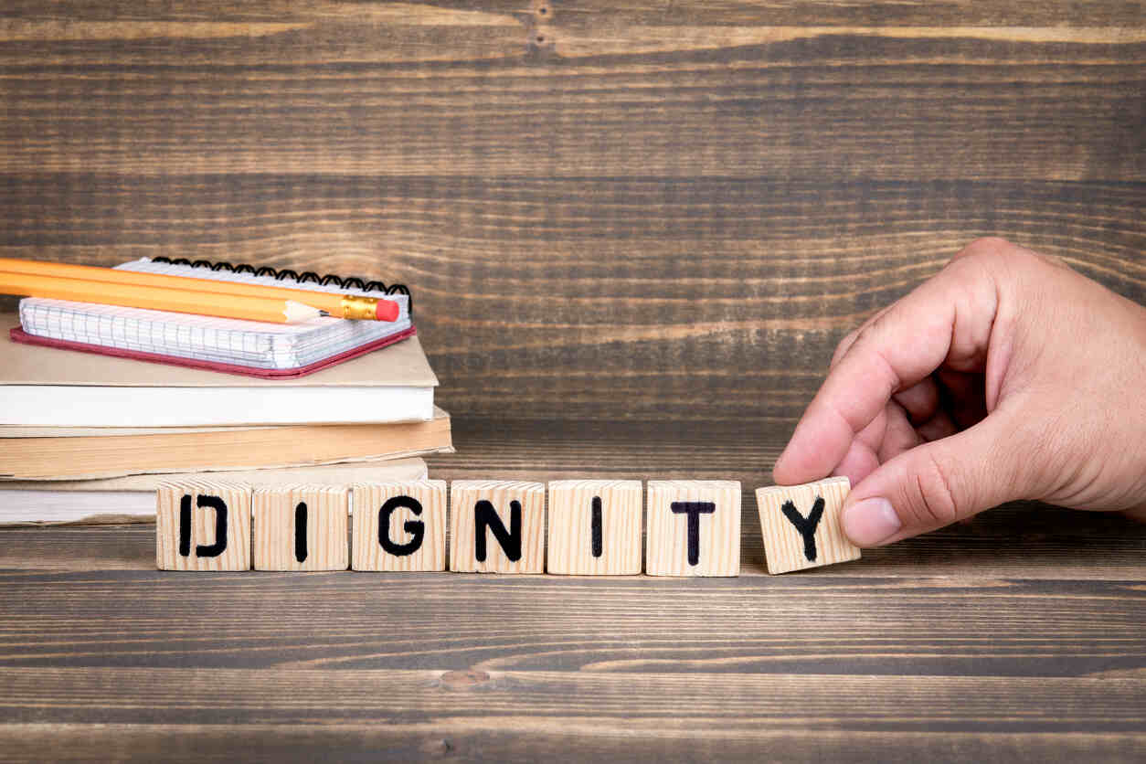 Hand arranging wooden blocks spelling DIGNITY, symbolizing the DIGNITY Act for Texas immigrants.