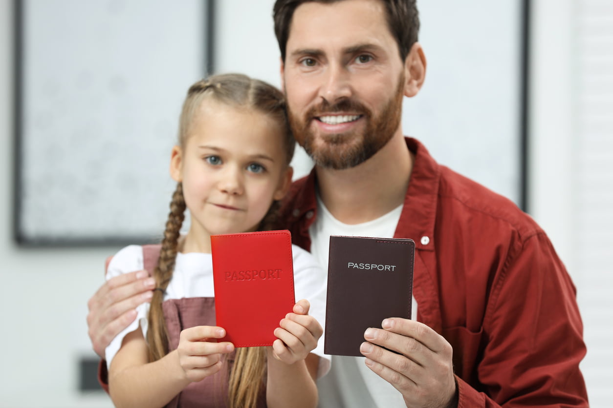 he image shows a father and his daughter holding their passports, smiling together.